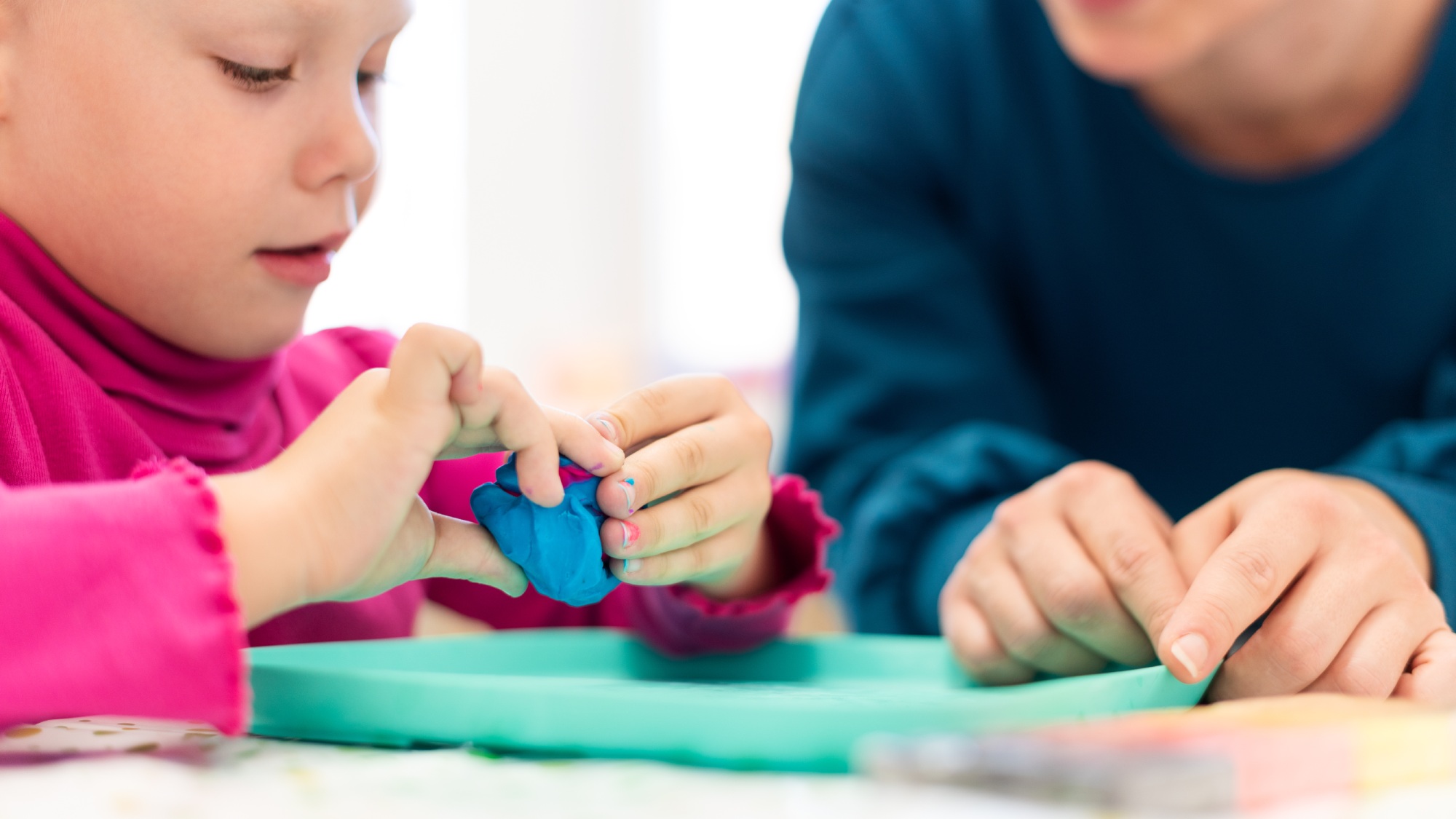 Kleinkindmädchen in der Ergotherapie-Sitzung für Kinder, die mit ihrem Therapeuten sensorische spielerische Übungen machen.